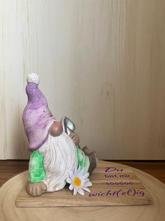Sitzender Wichtel mit lila Mütze, Klötzchenleiste und Text