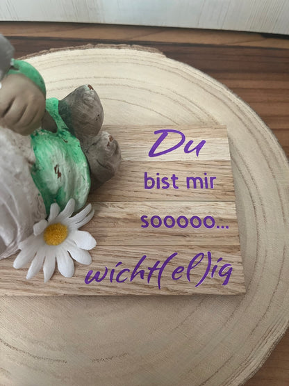 Sitzender Wichtel mit lila Mütze, Klötzchenleiste und Text